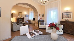 A spacious living room with a fireplace, a dining area with a table and chairs, and a cozy seating area with a sofa and armchairs. - Villa Beba, Castellina in Chianti, Siena and Chianti (Castellina in Chianti)