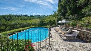 A swimming pool with lounge chairs and an umbrella, surrounded by stone walls and greenery. - Il Boschetto, Radda in Chianti, Siena and Chianti (Radda in Chianti)