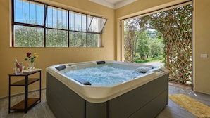 A hot tub in a room with large windows and a view of a garden. - Il Boschetto, Radda in Chianti, Siena and Chianti (Radda in Chianti)