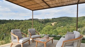 Un espace extérieur aménagé avec des chaises en osier et une table en bois, offrant une vue sur un paysage verdoyant et luxuriant.