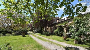 A garden path leading to a rustic building with stone walls and a covered patio area.