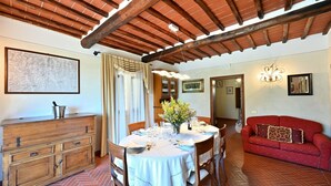 Comedor con mesa de madera dispuesta para cuatro, un sofá rojo y un mapa en la pared.