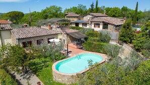 Una villa con piscina rodeada de exuberante vegetación y edificios de piedra.