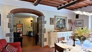 Comedor con una mesa lista para una comida, una chimenea y un pasillo que conduce a otra habitación.