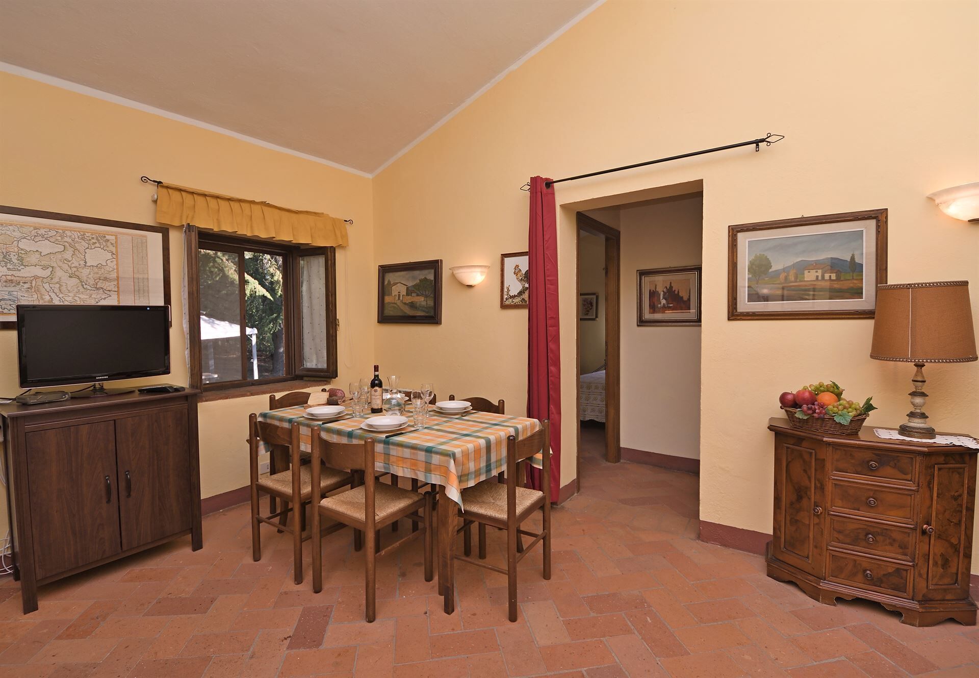 Un coin repas avec une table dressée pour quatre personnes, un téléviseur et un meuble avec des tiroirs.