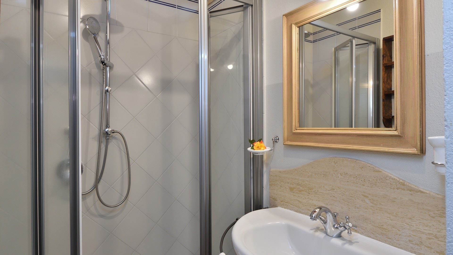 A bathroom with a glass-enclosed shower, a sink with a single faucet, and a mirror with a wooden frame.