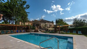 Ein Swimmingpool mit Liegestühlen und ein Steinhaus im Hintergrund.
