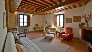 A cozy living room with a wooden ceiling, a fireplace, and a stone wall. - Mastro 3, San Sano, Gaiole in Chianti, Siena and Chianti (Gaiole in Chianti)