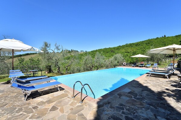 A swimming pool with lounge chairs and umbrellas, surrounded by stone flooring and olive trees. - La Querce, Rocca di Castellina, Castellina in Chianti, Siena and Chianti (Castellina in Chianti)
