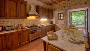 A kitchen with wooden cabinets, a gas stove, and a tiled backsplash. - Palazzo Rosadi, Monterchi, Arezzo and Cortona (Monterchi)