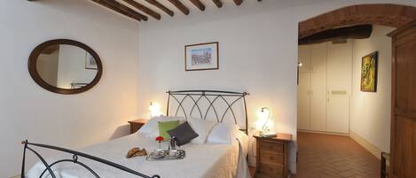 A bedroom with a bed, bedside tables, a mirror, and a framed picture on the wall.