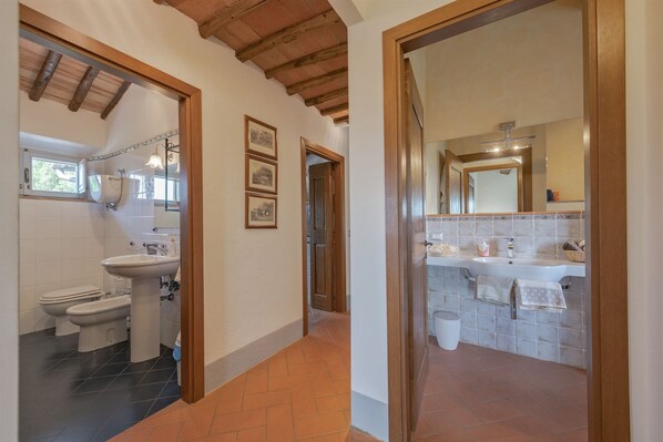 Un bagno con lavandino, specchio e due servizi igienici.