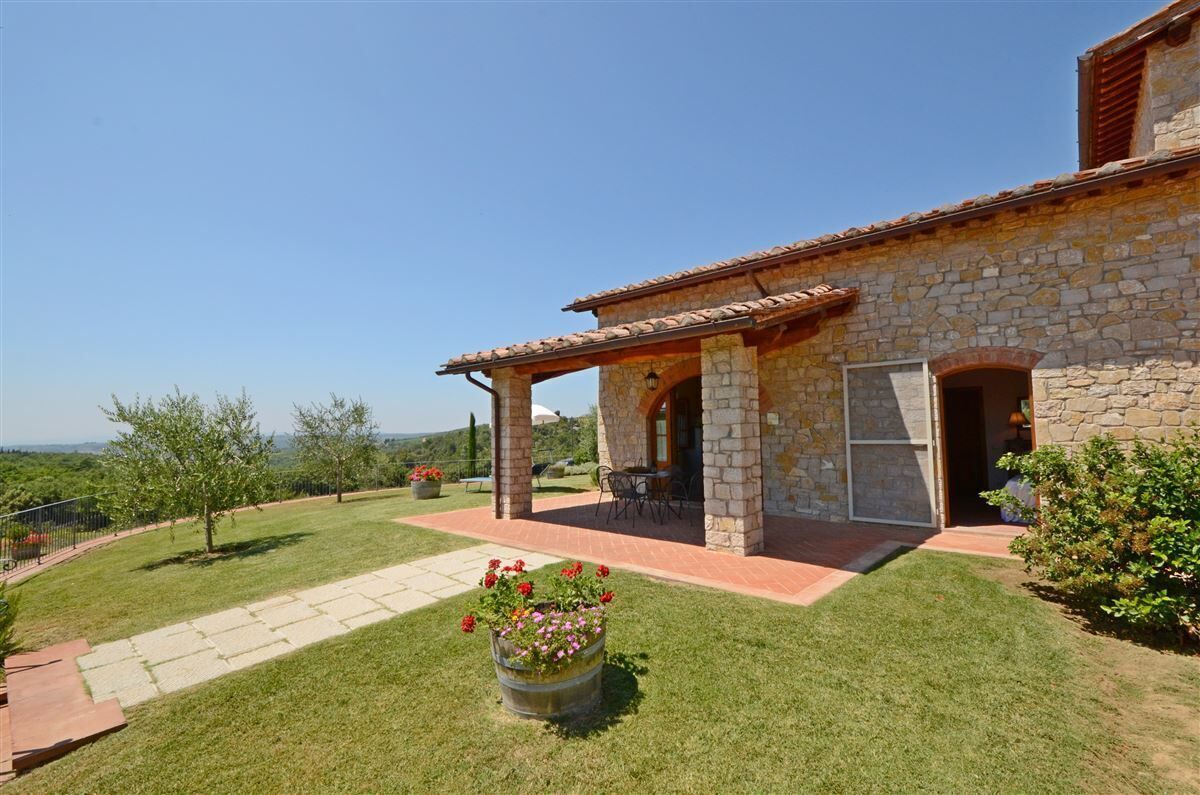 Un edificio in pietra con un patio, una zona relax coperta e vista sulla campagna.