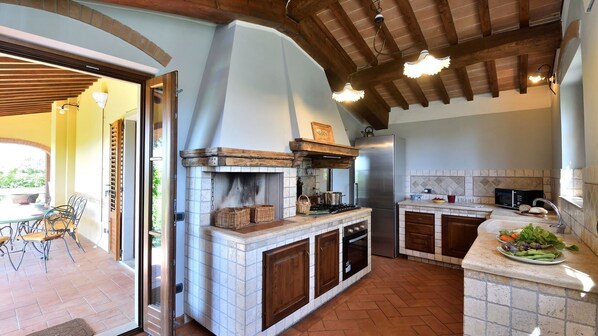 A kitchen with a built-in stove, a refrigerator, and a sink. There is a dining area with a table and chairs.