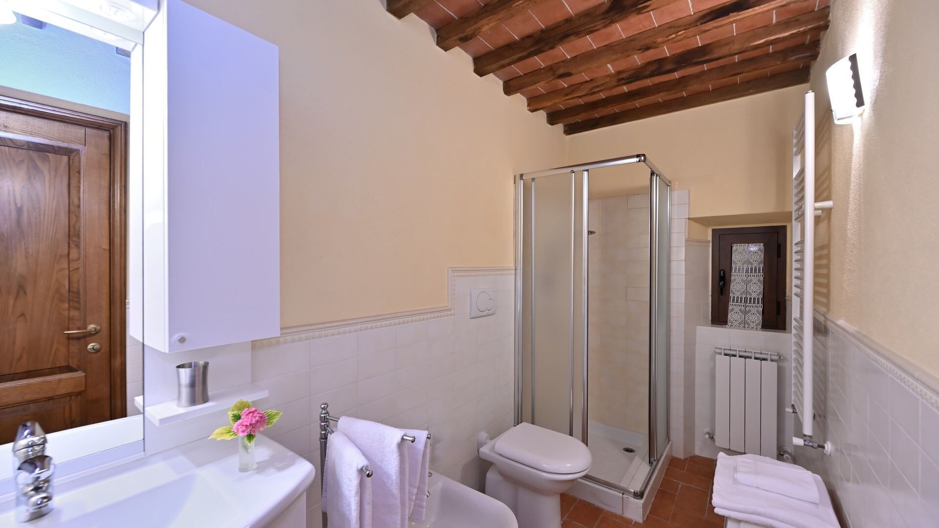 A bathroom with a shower, toilet, sink, and a wooden door.
