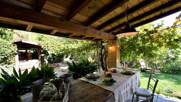An outdoor dining area with a wooden table set for two, surrounded by potted plants and a rustic brick wall. - Il Paretaio, Montevarchi, Arezzo and Cortona (Montevarchi)