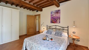Une chambre avec un lit, un plafond en bois, une armoire blanche, un tableau, des lampes de chevet et un plateau avec des éléments pour le petit-déjeuner.