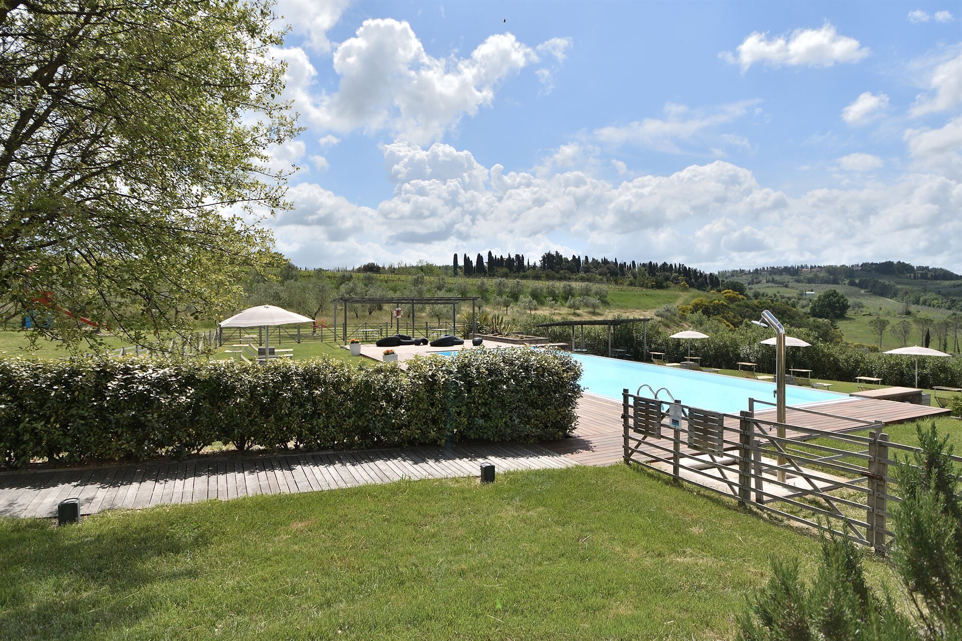 Zona de piscina con una pérgola, asientos y vistas al campo.