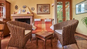 A cozy living room with wicker furniture, a fireplace, and a painting on the wall. - Ciacchieri, Gaiole in Chianti, Siena and Chianti (Gaiole in Chianti)