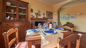 A dining room with a wooden table set for four, a cabinet with dishes, and a fireplace. - Ciacchieri, Gaiole in Chianti, Siena and Chianti (Gaiole in Chianti)