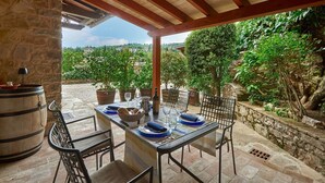 An outdoor dining area with stone walls, potted plants, and a view of a hillside. - Ciacchieri, Gaiole in Chianti, Siena and Chianti (Gaiole in Chianti)