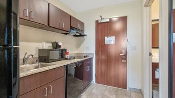 A kitchen with dark wooden cabinets, a stainless steel sink, a microwave, and a dishwasher.