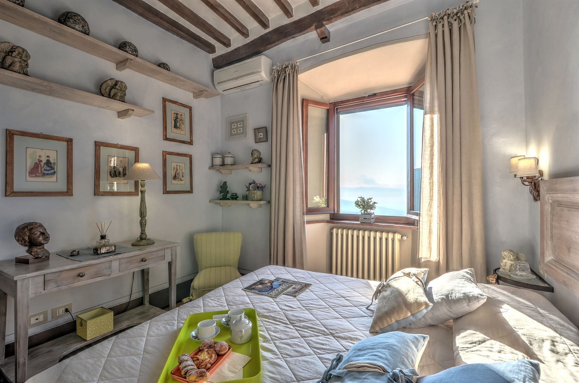 A bedroom with a bed, a desk, and a window with a view.