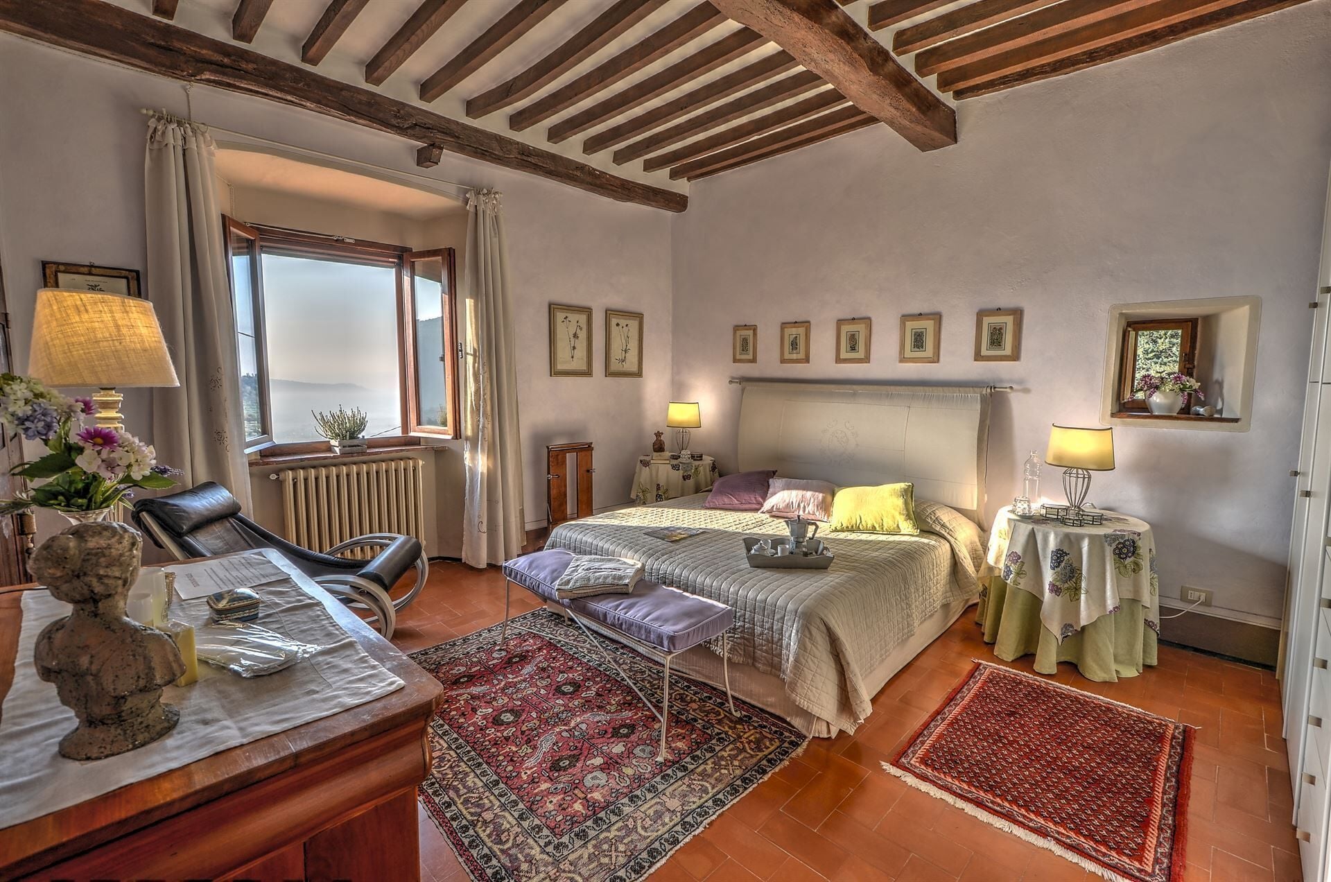 Un dormitorio acogedor con una cama grande, un escritorio con lámpara, una silla y vistas al exterior a través de una ventana.
