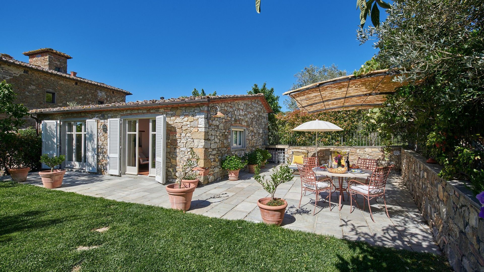 A stone house with a patio, outdoor seating, and potted plants.