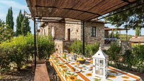 An outdoor dining area with a table set for breakfast, surrounded by stone buildings and greenery.