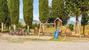 A playground with a swing set, slide, and bicycles parked nearby.
