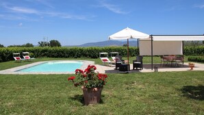 Zona de piscina con sillones de descanso y un área de estar cubierta.