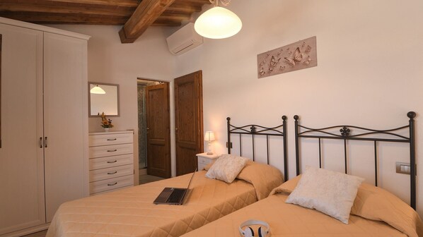 Quarto com duas camas, penteadeira, espelho, porta e uma obra de arte na parede.
