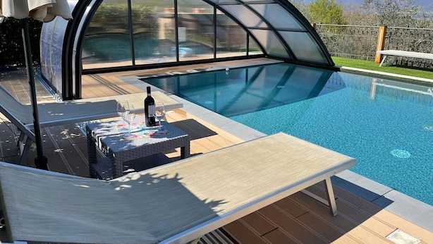 A swimming pool with a glass-enclosed deck, a lounge chair, and a table with a bottle and glasses. - Casa di Campagna Pianelli, Pergine Valdarno, Arezzo and Cortona (Pergine Valdarno)