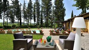 En terrasse med fletmøbler, et glasbord og en swimmingpool.