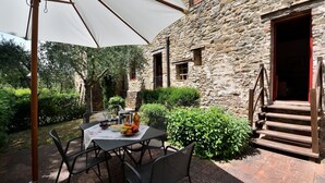 An outdoor dining area with a table set for two, surrounded by stone walls and greenery. - Raffaello, Montefienali, Gaiole in Chianti, Siena and Chianti (Gaiole in Chianti)