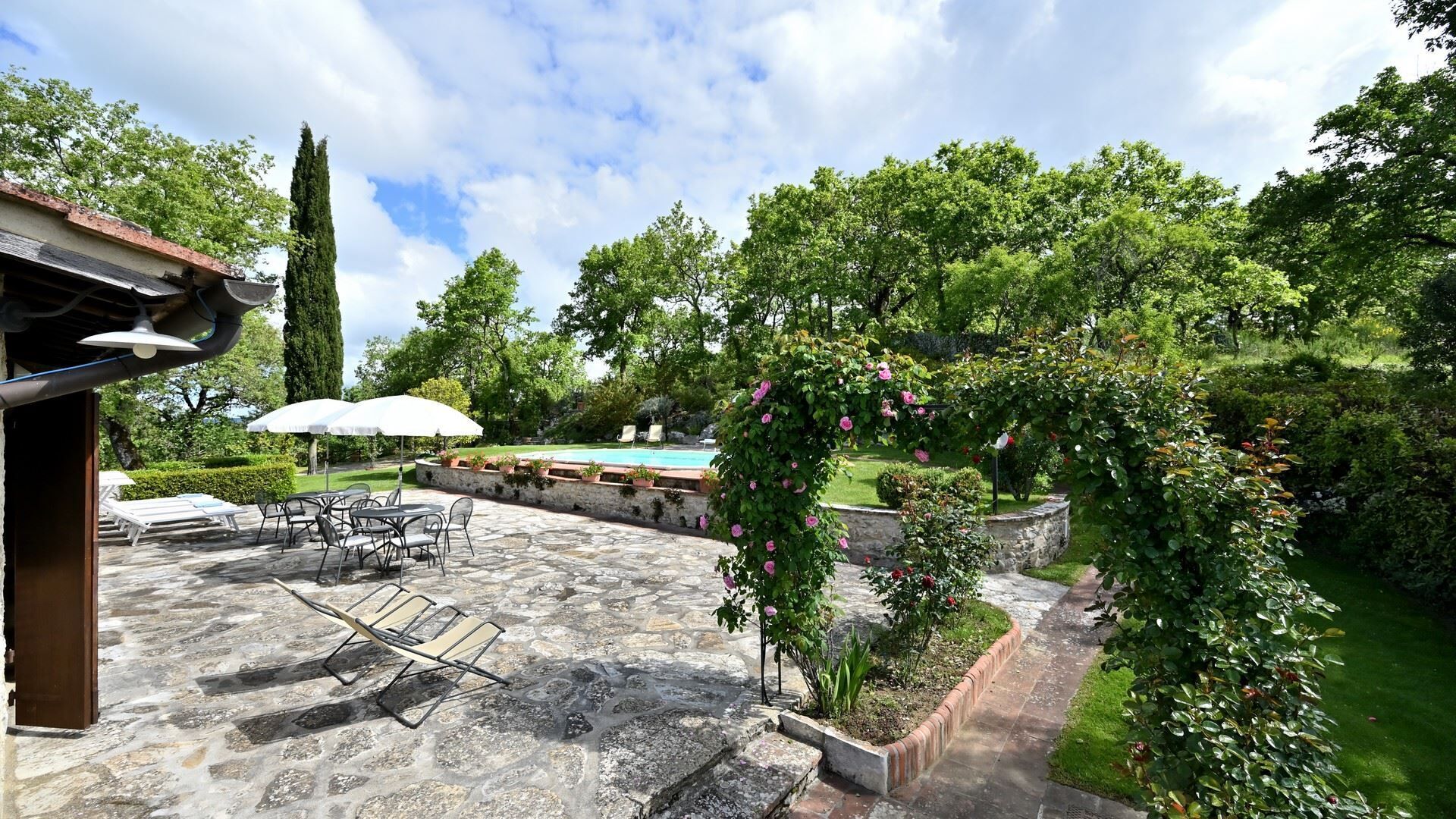 A patio area with stone flooring, outdoor furniture, and a swimming pool.