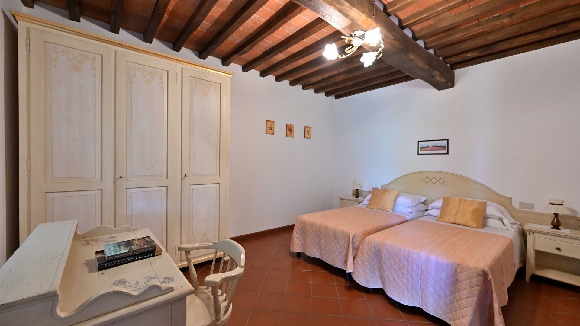 A bedroom with two beds, a desk with a chair, and a wardrobe.