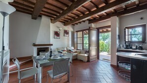 Uma sala de jantar com mesa posta para quatro pessoas, lareira e vista para o exterior através de uma grande janela.
