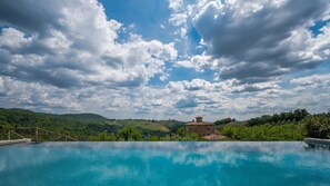 Ein klares, blaues Schwimmbecken mit Blick auf einen Hügel und ein Gebäude im Hintergrund.