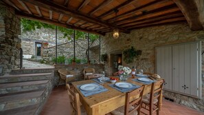 A rustic stone building with a wooden dining table set for six, surrounded by wicker chairs. - L'Agrifoglio, Gaiole in Chianti, Siena and Chianti (Gaiole in Chianti)