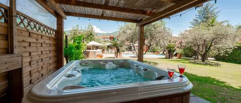Un jacuzzi con cubierta de madera y una pérgola arriba.