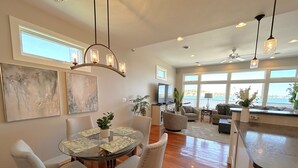 A spacious living room with a glass dining table, comfortable seating, and a view of the outdoors. - St Ignace Loft - Downtown St Ignace (Saint Ignace)