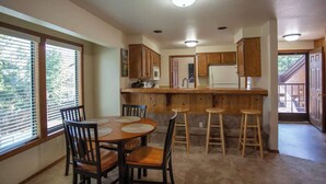 Una cocina con armarios de madera, una isla central con taburetes y una mesa de comedor con sillas.