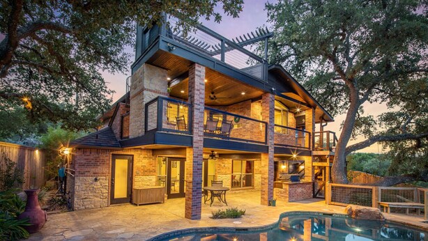 A two-story house with a swimming pool, outdoor seating, and a large tree in the background. - Hummingbird Hideaway - Canyon Lake Waterfront + Pool & Hot Tub + Game Room + Covered Patios (Canyon Lake)
