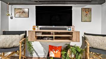 Un salon moderne doté d’un grand téléviseur à écran plat, de deux fauteuils confortables et d’un meuble de rangement en bois pour les appareils multimédias.
