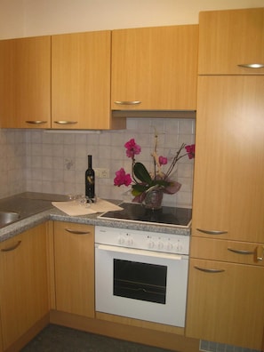 A kitchen with wooden cabinets, a Siemens stove, and a vase with pink flowers. - Chalet Sonnblick - Apartment III (Außerrotte)