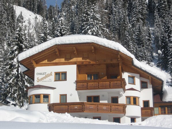 A chalet with a wooden balcony, surrounded by snow-covered trees. - Chalet Sonnblick - Apartment III (Außerrotte)