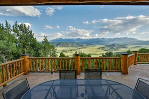 Une terrasse avec une table et des chaises, offrant une vue sur un paysage montagneux.