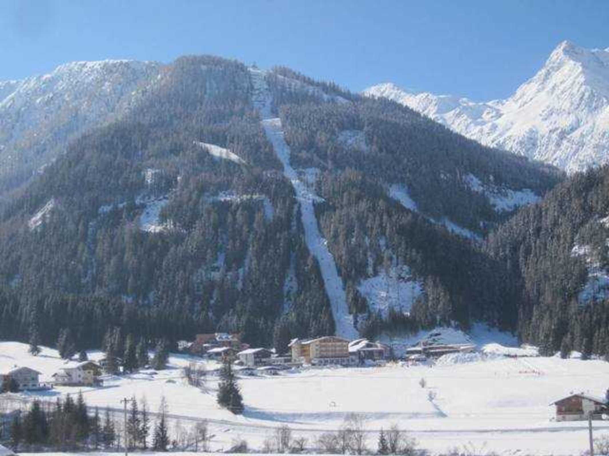 Een berglandschap met sneeuw en een skigebied, inclusief gebouwen en skipistes.